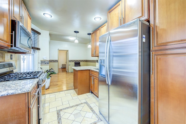 kitchen with light stone countertops, hanging light fixtures, stainless steel appliances, and light wood-type flooring