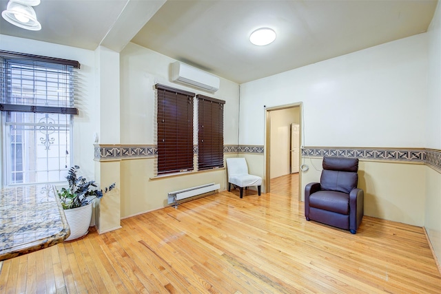 living area with baseboard heating, light hardwood / wood-style floors, and an AC wall unit