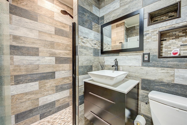 bathroom with walk in shower, vanity, tile walls, and toilet