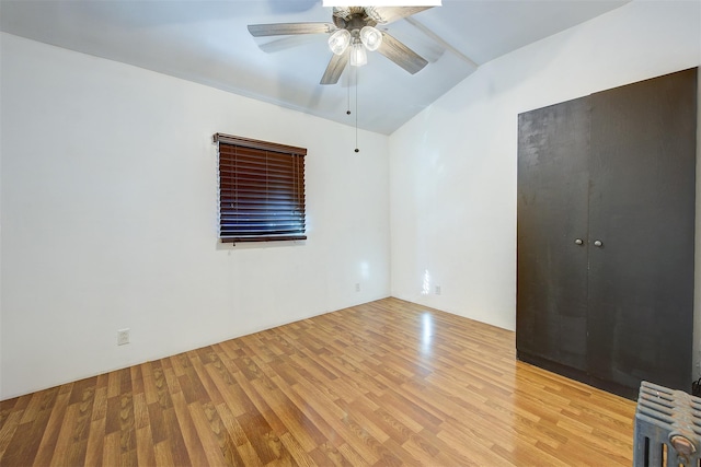 empty room featuring ceiling fan, radiator heating unit, and light hardwood / wood-style floors