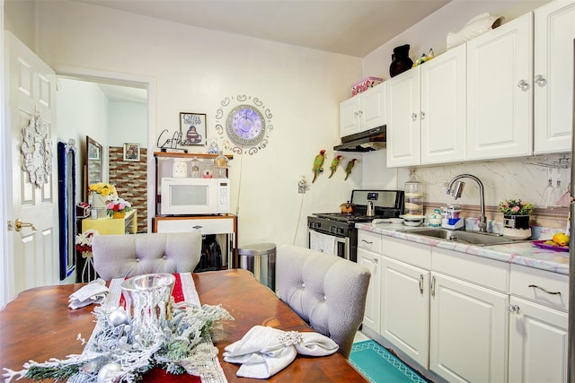 kitchen featuring backsplash, stainless steel range with gas cooktop, sink, and white cabinets