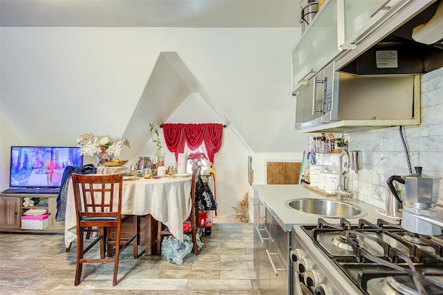 kitchen featuring decorative backsplash, stainless steel stove, light hardwood / wood-style floors, and sink