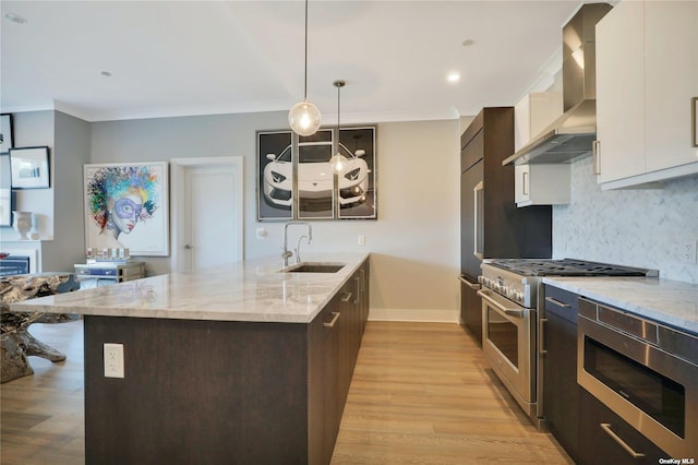 kitchen with white cabinets, hanging light fixtures, sink, wall chimney exhaust hood, and appliances with stainless steel finishes