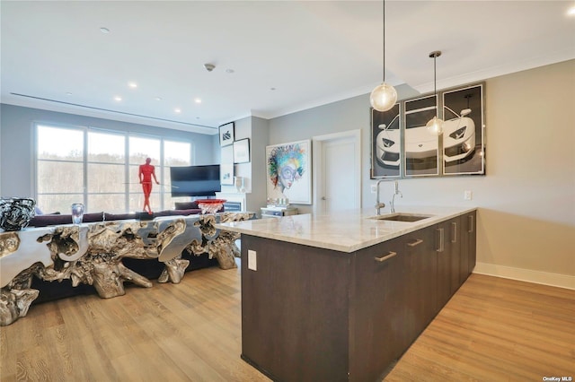 kitchen with kitchen peninsula, dark brown cabinetry, sink, decorative light fixtures, and light hardwood / wood-style floors