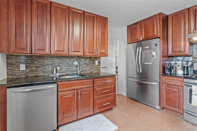 kitchen with sink, stainless steel appliances, tasteful backsplash, dark stone countertops, and light tile patterned floors