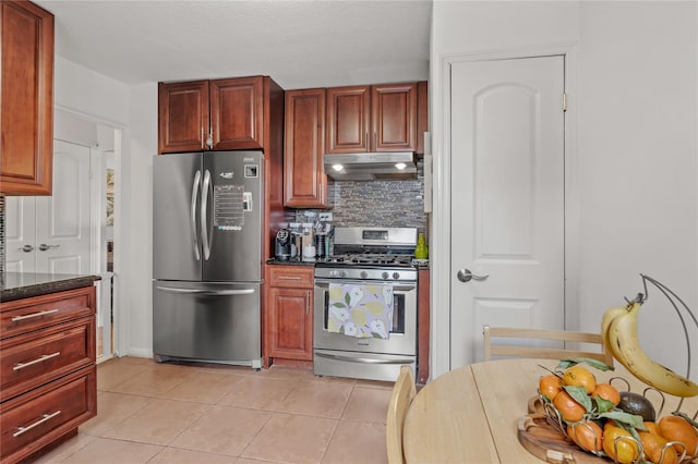 kitchen featuring tasteful backsplash, dark stone countertops, light tile patterned floors, and stainless steel appliances