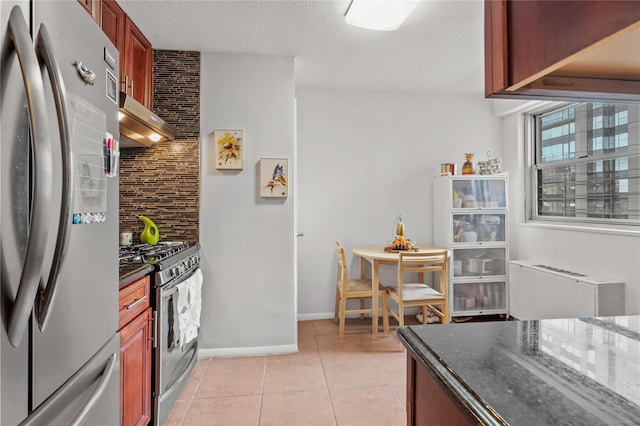 kitchen featuring decorative backsplash, dark stone counters, a textured ceiling, stainless steel appliances, and light tile patterned floors