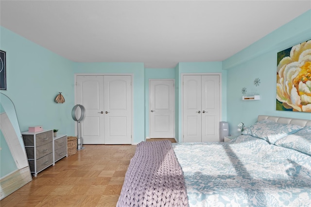 bedroom featuring multiple closets and light parquet flooring