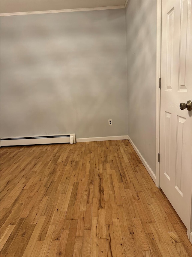 spare room with crown molding, light hardwood / wood-style floors, and a baseboard heating unit