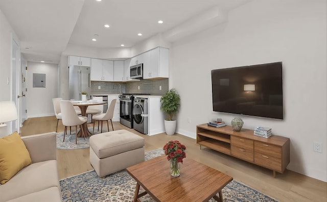 living room featuring light wood-type flooring, electric panel, and sink