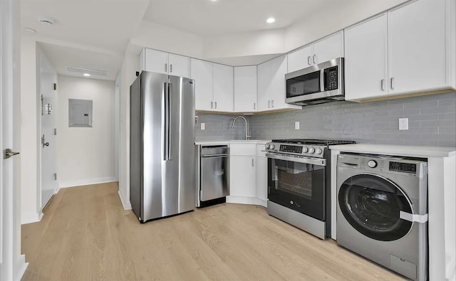 kitchen with backsplash, light hardwood / wood-style floors, stainless steel appliances, washer / clothes dryer, and white cabinetry