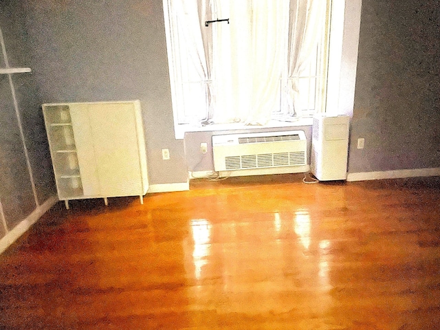 spare room with a wall mounted air conditioner and hardwood / wood-style floors