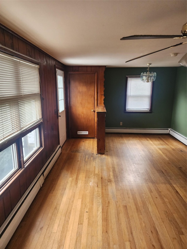 interior space with light wood-type flooring, baseboard heating, and a wealth of natural light