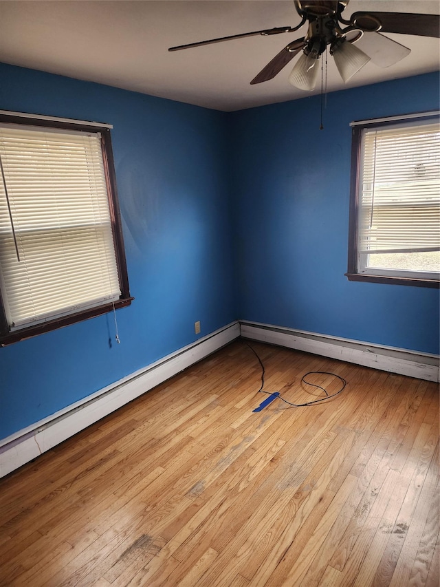 spare room featuring ceiling fan, light wood-type flooring, and a baseboard heating unit