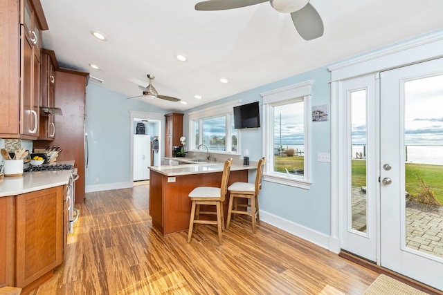 kitchen featuring a kitchen breakfast bar, sink, gas range, light hardwood / wood-style floors, and kitchen peninsula