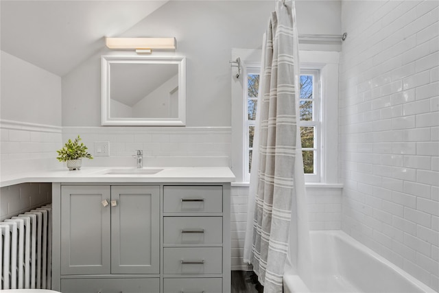 bathroom featuring lofted ceiling, tile walls, radiator heating unit, vanity, and shower / bath combination with curtain