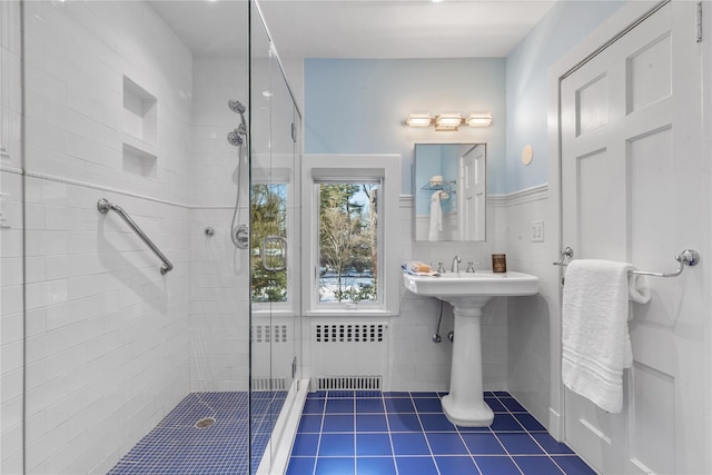 bathroom with radiator, a shower with door, and tile walls