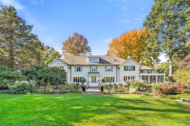 back of house with a sunroom and a lawn