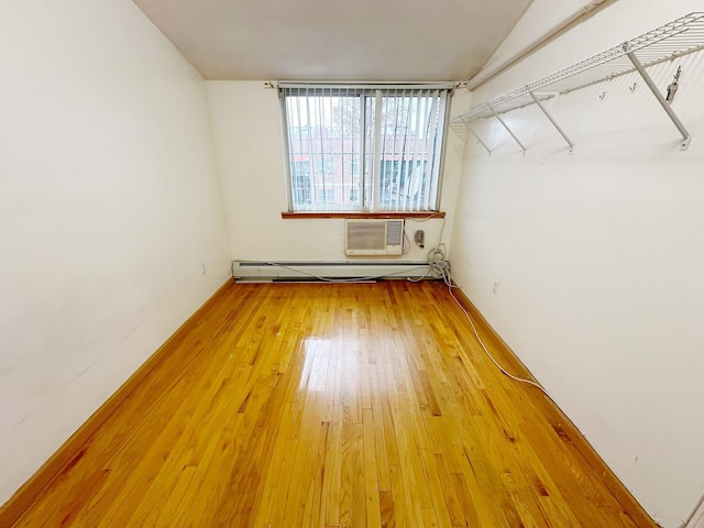 empty room with hardwood / wood-style floors, a wall mounted AC, and a baseboard heating unit