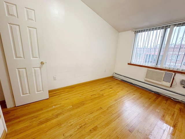 spare room featuring light wood-type flooring, baseboard heating, and an AC wall unit