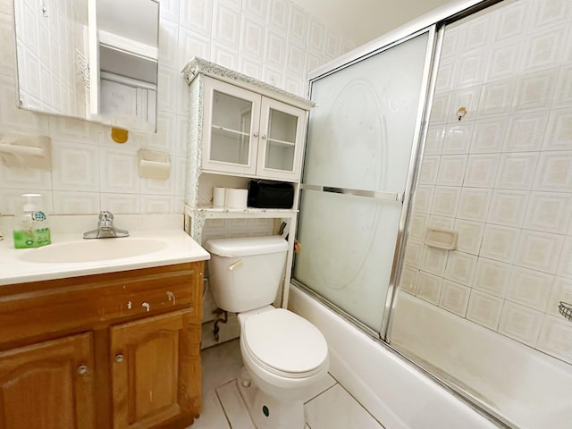 full bathroom featuring enclosed tub / shower combo, tile patterned floors, toilet, vanity, and tile walls