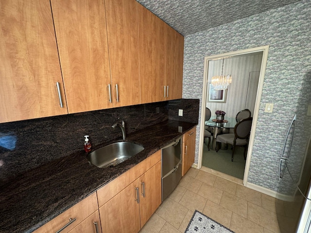 kitchen featuring sink, light tile patterned flooring, dark stone counters, and stainless steel dishwasher