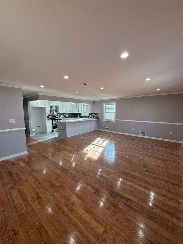 unfurnished living room featuring hardwood / wood-style flooring and crown molding