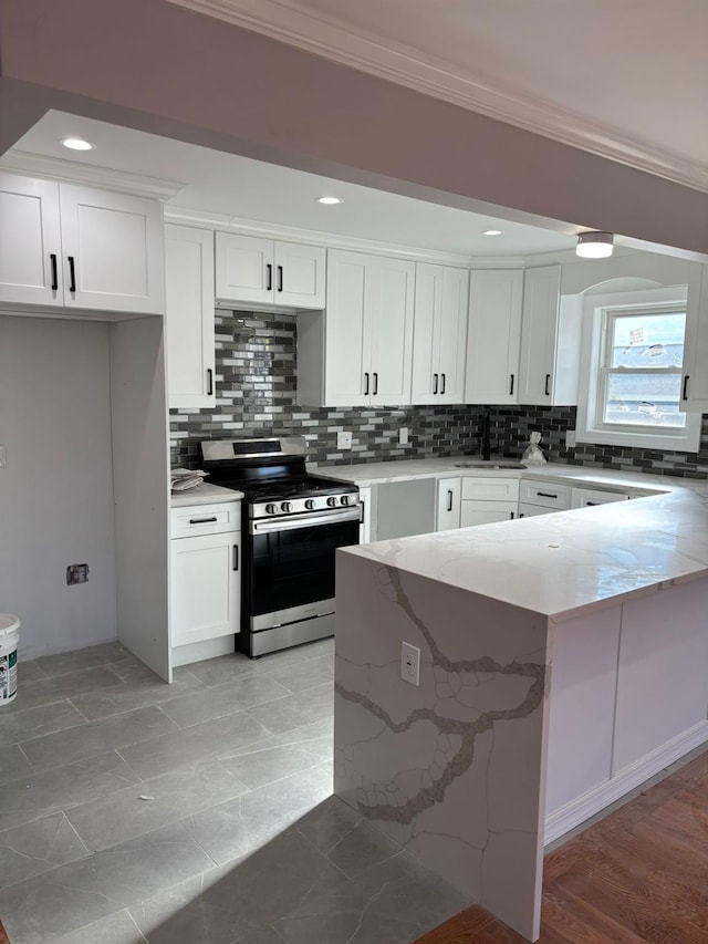 kitchen featuring crown molding, white cabinets, light stone counters, and stainless steel range oven