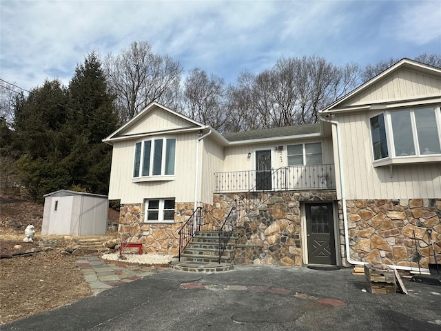 view of front facade featuring an outbuilding, stone siding, and a shed