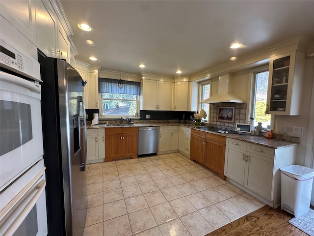 kitchen featuring black appliances, a sink, recessed lighting, wall chimney exhaust hood, and light tile patterned floors