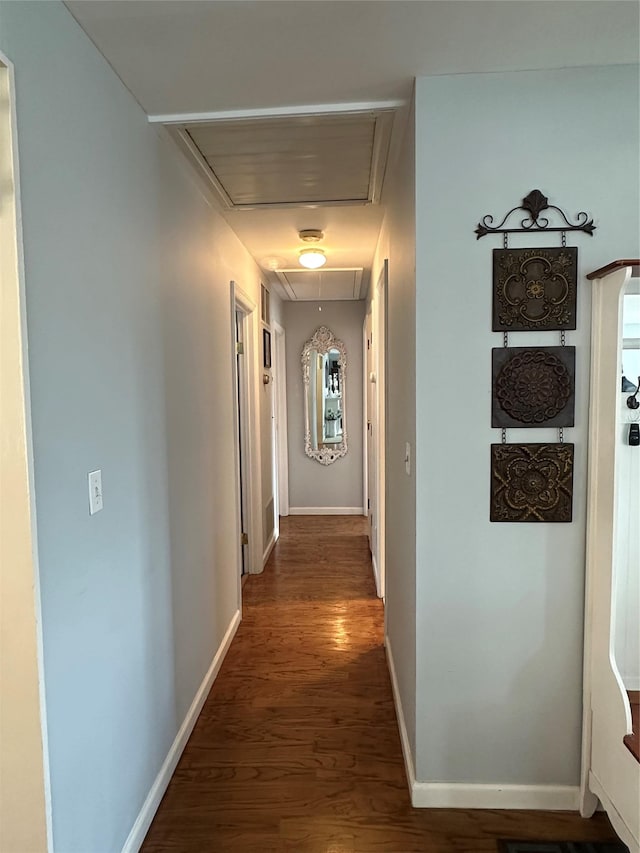 hall featuring attic access, wood finished floors, and baseboards