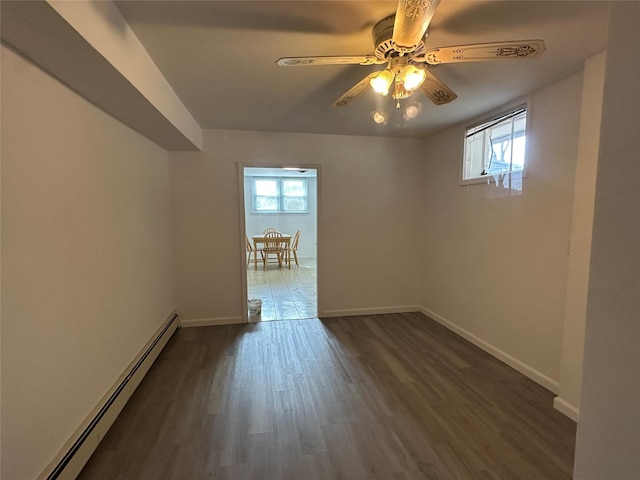 empty room with dark wood-style flooring, a ceiling fan, baseboards, and a baseboard radiator