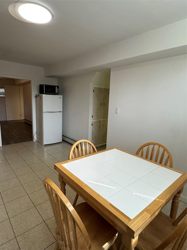 dining room featuring light tile patterned floors and a baseboard heating unit