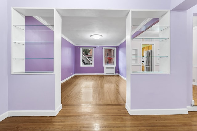 foyer entrance with radiator heating unit, hardwood / wood-style floors, and ornamental molding