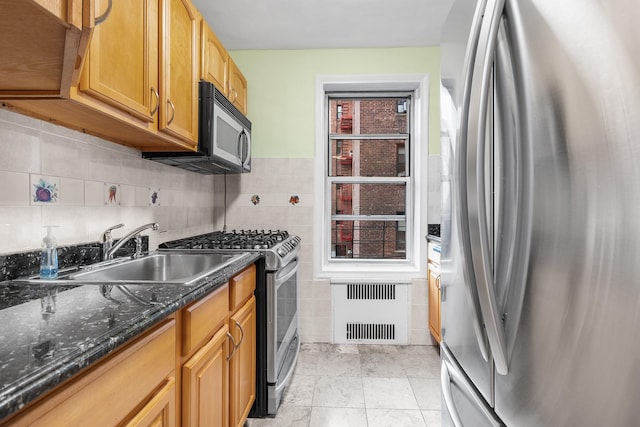 kitchen with sink, plenty of natural light, dark stone counters, tile walls, and appliances with stainless steel finishes