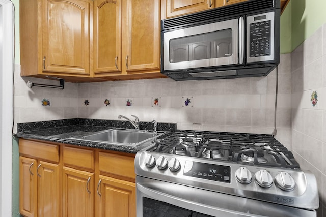 kitchen featuring stainless steel appliances, tasteful backsplash, dark stone counters, and sink