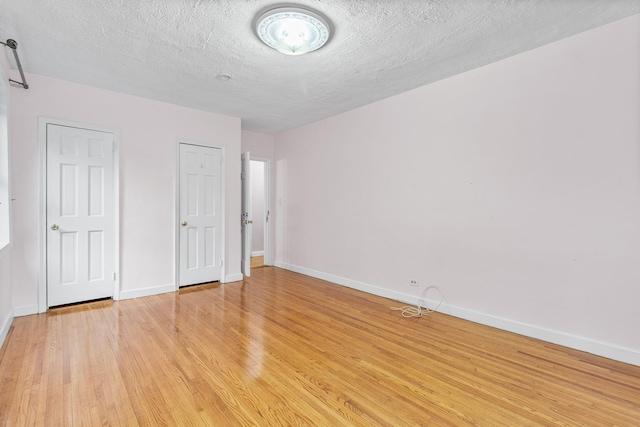 unfurnished bedroom with a textured ceiling and light hardwood / wood-style flooring