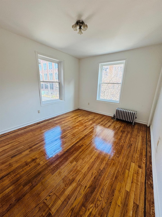 spare room with hardwood / wood-style floors and radiator heating unit