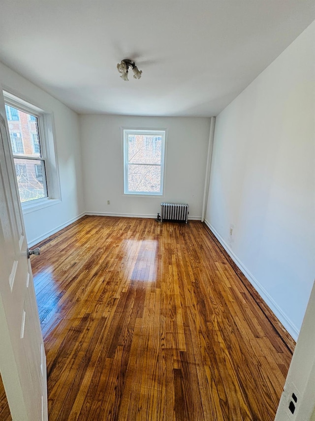 spare room featuring radiator and hardwood / wood-style flooring