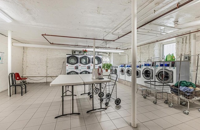 laundry room featuring stacked washer / drying machine, a wealth of natural light, and washing machine and clothes dryer