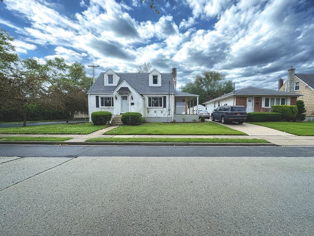 33 Farnum St, Lynbrook, NY 11563 - cape cod-style house featuring a front yard, concrete driveway, and a chimney