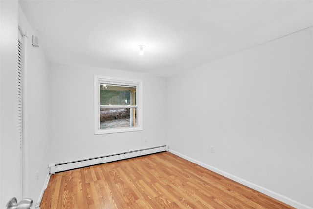 unfurnished room with baseboard heating and hardwood / wood-style flooring