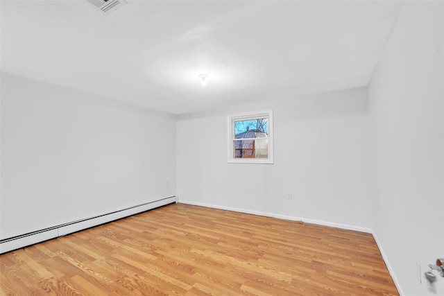 empty room with light hardwood / wood-style floors and baseboard heating