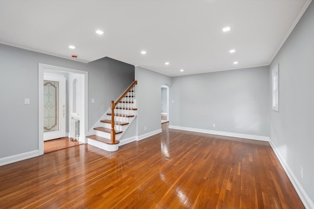 unfurnished living room with wood-type flooring and ornamental molding