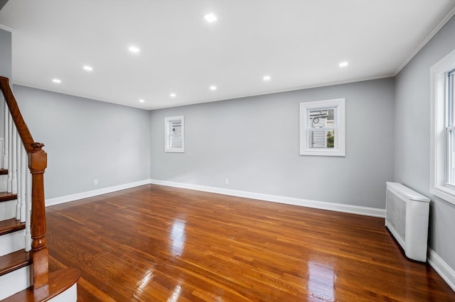 interior space with a wealth of natural light, dark hardwood / wood-style flooring, ornamental molding, and radiator heating unit