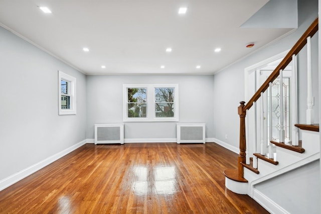 interior space with light wood-type flooring, ornamental molding, and radiator