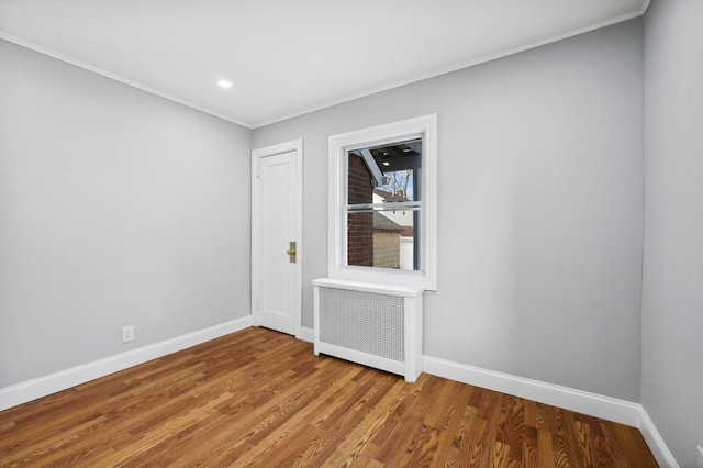 spare room with wood-type flooring, ornamental molding, and radiator