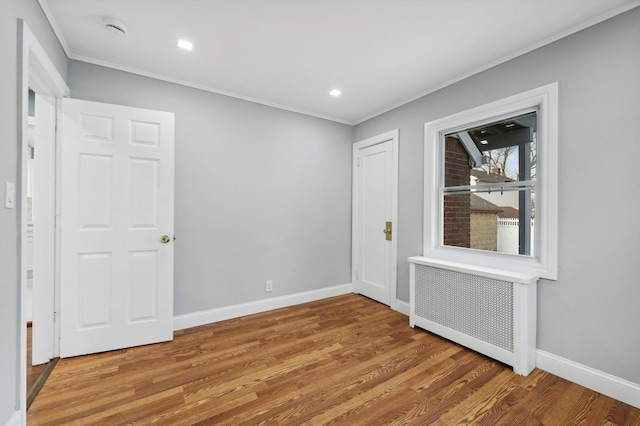 empty room with radiator heating unit, crown molding, and wood-type flooring