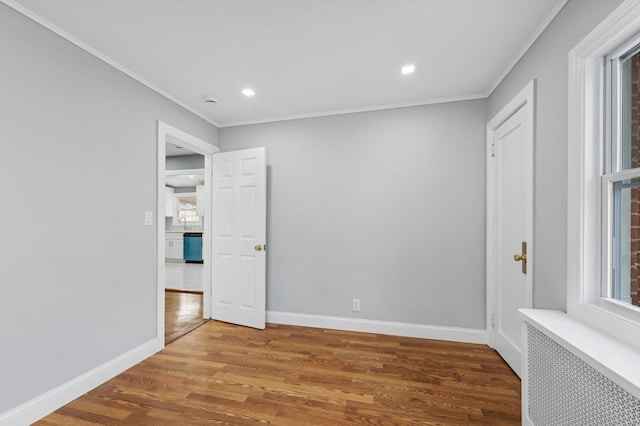 spare room featuring radiator heating unit, wood-type flooring, and ornamental molding