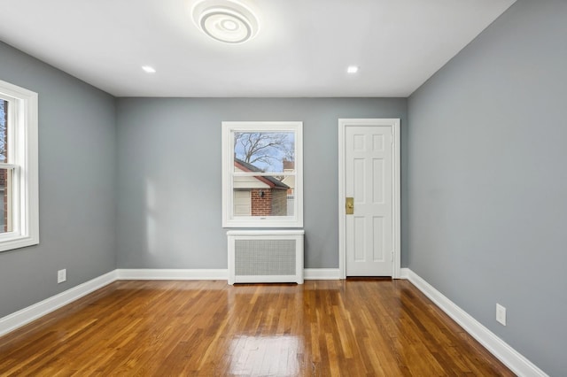 empty room featuring radiator heating unit and hardwood / wood-style floors